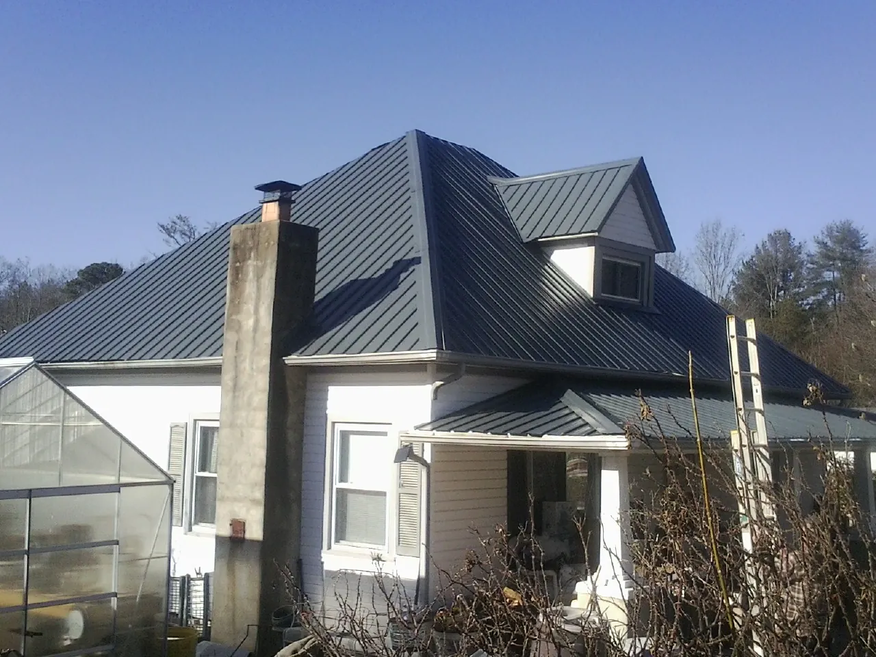 Dark blue standing seam metal roof on a white farmhouse with dormer — Slate & Tile Roof Repair by Roofing Brothers in La Habra