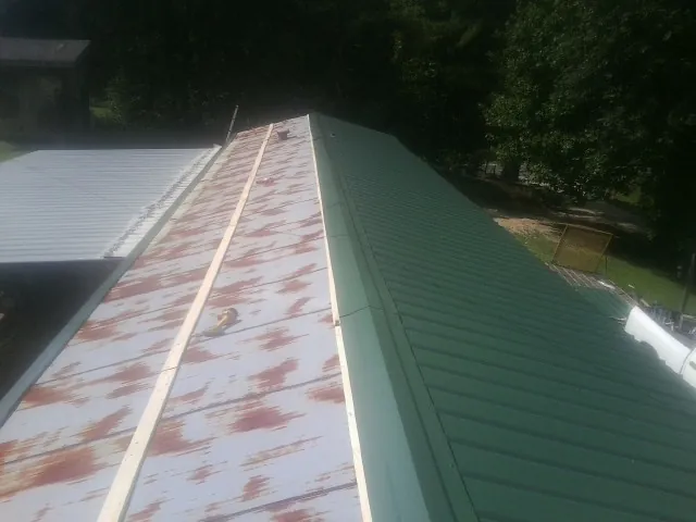 Old rusted panels beside newly installed green metal roofing — Wind Damage Roof Repair by Roofing Brothers in La Habra