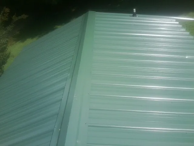 New green metal panels meeting at the ridge of a roof — Flat Roof Repair work by our crew in La Habra
