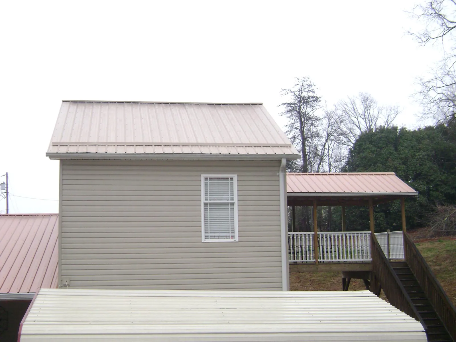 Tan metal roofs on a two story addition and attached porch, from a Roof Replacement job in La Habra