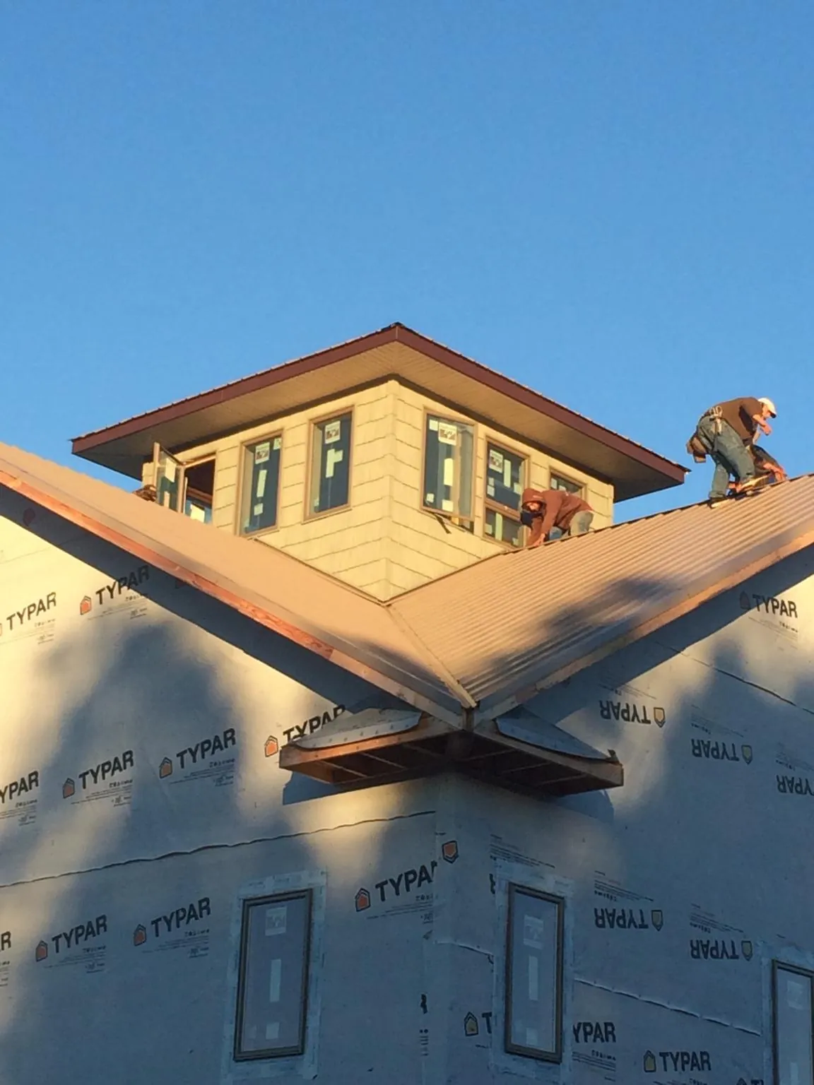 Roofers working around a rooftop cupola on a new metal roof at sunset — Roof Waterproofing in La Habra by Roofing Brothers
